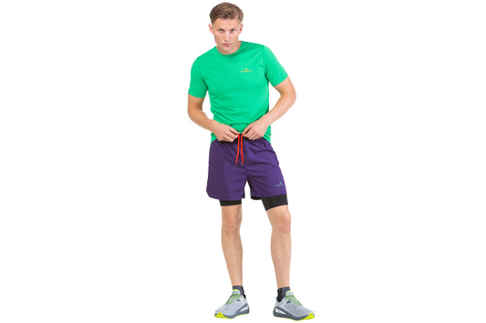 Mens running shorts - The men's tech revive 5 inch twin shorts by Ronhill is made of a light-weight, breathable material made from recycled yarn. It has a relaxed fit, a secure outer pocket, stretch for added movement, reflective strips to help you be seen and wicking to keep you dry. This item comes in imperial black and the photo is a side view of the shorts being worn by someone